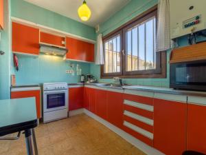 a kitchen with orange and green cabinets and a microwave at Holiday Home Flor de Lis by Interhome in Torredembarra