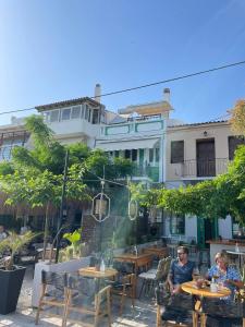 dwoje osób siedzących przy stolikach przed restauracją w obiekcie Aegean Blu Port House Pythagoreio w mieście Pitagorio