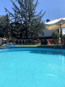 uma grande piscina azul com um guarda-sol em casa nonna Rica 