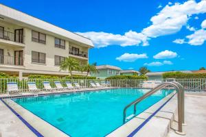 una piscina frente a un edificio con sillas en Absolute Anna Maria-Private Beach Access-Heated Pool-Water Views From Every Room, en Bradenton Beach