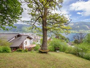 un banco sentado bajo un árbol al lado de una casa en Holiday Home Karin by Interhome, en Zell am See