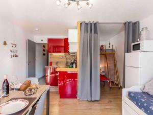 a kitchen with red cabinets and a table in a room at Studio Vostok Zodiaque-91 by Interhome in Le Corbier +28 photos