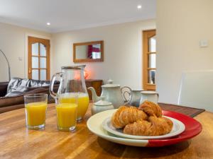 una mesa con un plato de bollería y dos vasos de zumo de naranja en Holiday Home Silver Birch by Interhome, en Drumnadrochit