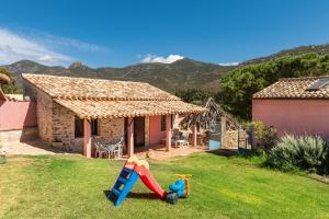 una casa con un cortile con scivolo e parco giochi di Villa Bella Solanas - Cuili Murvoni a Solanas