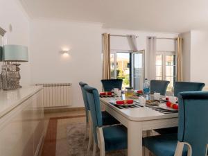 a white dining room with a table and blue chairs at Holiday Home Girassol by Interhome in Cascais