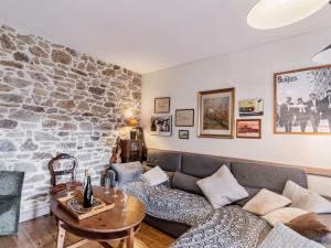 a living room with a couch and a stone wall at Holiday Home Les Roses by Interhome in Yffiniac