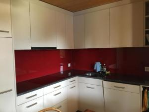 - une cuisine avec des placards blancs et des murs rouges dans l'établissement Apartment Forigel UG by Interhome, à Valbella