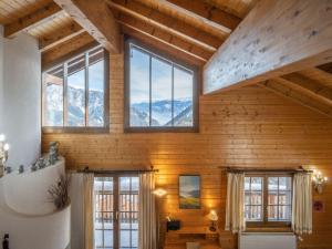 Habitación con paredes y ventanas de madera y montañas. en Chalet Le Sorbier by Interhome, en Chamoson