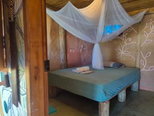 a small bed in a room with a canopy at Casa de Terra in Caraíva +11 photos