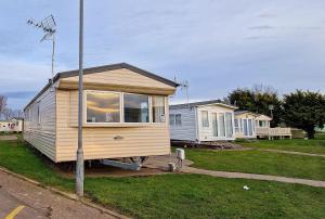 a tiny house sitting on the side of a street at 8 Berth Caravan With Wifi At Seawick Holiday Park Ref 27025r in Clacton-on-Sea
