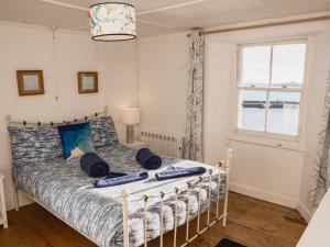 ein Schlafzimmer mit einem Bett mit blauen Kissen und einem Fenster in der Unterkunft Holiday Home Cliff Cottage by Interhome in Mevagissey