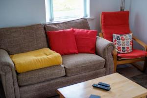 a living room with a couch and two red chairs at Mary Jane's Cottage, Lettermacaward in Doochary
