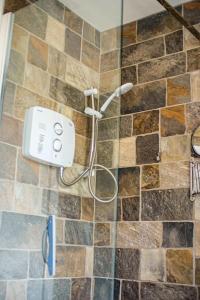 a shower in a bathroom with a tile wall at Mary Jane's Cottage, Lettermacaward in Doochary