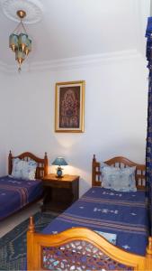 a bedroom with two beds and a table with a lamp at Dar El Goulli in Sousse