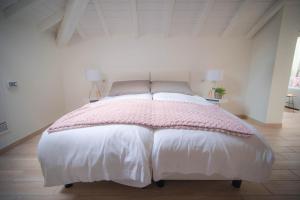 a white bedroom with a bed with a pink blanket at Comonfive Apartments in Como