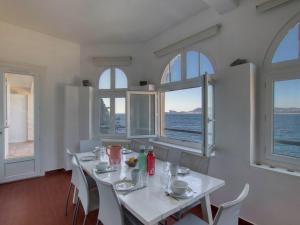 a dining room with a table with chairs and windows at Apartment la Rainette by Interhome in La Madrague