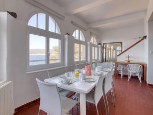 a dining room with white tables and chairs and windows at Apartment la Rainette by Interhome in La Madrague