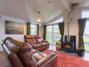 ein Wohnzimmer mit einem Ledersofa und einem Kamin in der Unterkunft Chalet Loch Leven Lodge 25 East by Interhome in Kinross