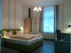 a bedroom with a bed and a chair and a window at Kurhotel Quellenhof in Bad Bertrich