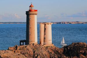 two lighthouses on a cliff with a sailboat in the water at Atelier Kersauson in Brest