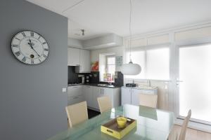 cocina con mesa de cristal y reloj en la pared en Hello Zeeland - Appartement Port Scaldis 19-042, en Breskens