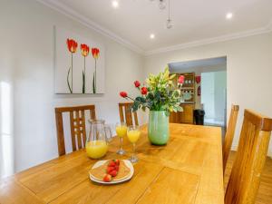 una mesa de comedor con un jarrón de flores y zumo de naranja en Holiday Home Brocks by Interhome, en Drumnadrochit