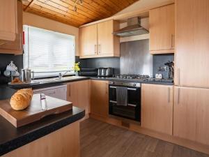 a kitchen with wooden cabinets and a stove top oven at Chalet Loch Leven Lodge 4 by Interhome in Kinross
