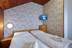 1 Schlafzimmer mit 2 Betten und einem TV an einer Backsteinwand in der Unterkunft Horská Chata Ještědka in Světlá pod Ještědem