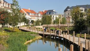een brug over een rivier in een stad met gebouwen bij L'escale du Trianon in Le Plessis-Robinson