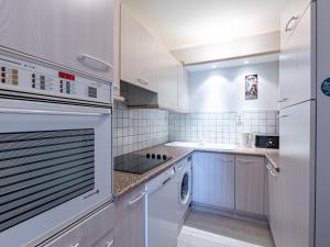 a kitchen with white cabinets and a washer and dryer at Apartment Le Galion-2 by Interhome in Dinard