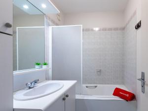 een witte badkamer met een wastafel en een bad bij Apartment Le Galion-2 by Interhome in Dinard