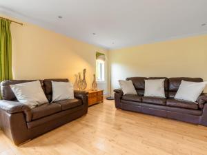 a living room with two brown leather couches at Holiday Home The Firs by Interhome in Drumnadrochit