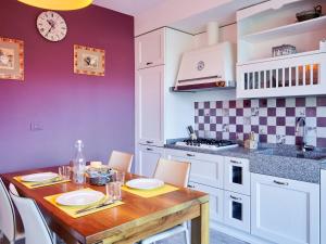 a kitchen with a wooden table with chairs and a kitchen with purple walls at Apartment Promessi Sposi by Interhome in Lecco