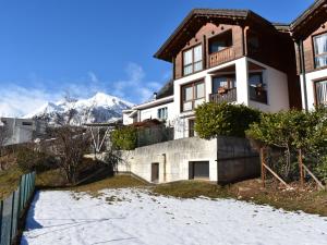 uma casa na neve com montanhas ao fundo em Apartment Rüthanet by Interhome em Airolo