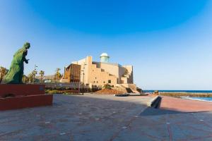 una statua di fronte a un edificio vicino all'oceano di Puccini Oasis - Sole e amore a Las Palmas de Gran Canaria