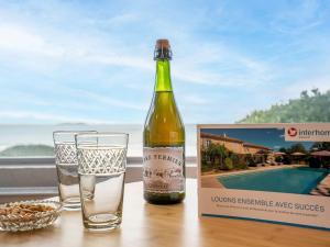 butelkę wina siedzącą na stole obok szklanki w obiekcie Holiday Home La longue vue by Interhome w Saint-Malo