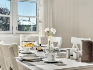 een witte eettafel met witte stoelen en een vaas met bloemen bij Holiday Home Ghita - 1-2km from the sea in Sealand by Interhome in Hornbæk