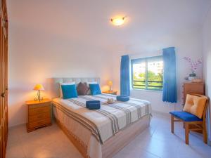 une chambre avec un lit, des rideaux bleus et une fenêtre dans l'établissement Apartment Garden Place by Interhome, à Armação de Pêra