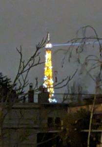 una torre illuminata in cima a un edificio di notte di Parisian Sparkle Retreat a Neuilly-sur-Seine