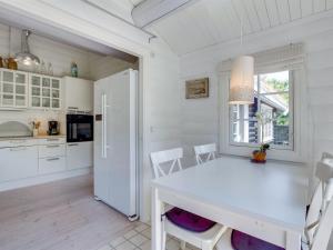 uma cozinha com uma mesa branca e um frigorífico branco em Holiday Home Ottil - 1km from the sea in Sealand by Interhome em Tisvildeleje