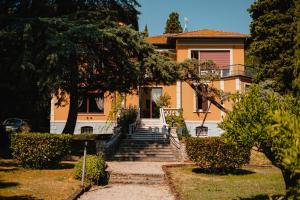 uma casa amarela com escadas em frente em Villa Mimosa au Lac - Estella Hotels Italia em Toscolano Maderno