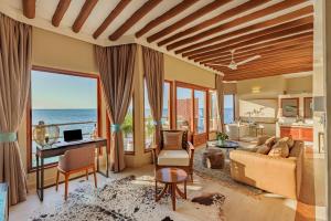 a living room with a view of the ocean at Konokono Beach Resort and Isaraya Luxury Overwater Villas in Michamvi