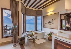 La salle de bains est pourvue d'une baignoire et offre une vue sur l'océan. dans l'établissement Konokono Beach Resort and Isaraya Luxury Overwater Villas, à Michamvi