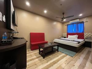 グワーハーティーにあるThe Rhinoのベッド1台と赤い椅子が備わる小さな客室です。
