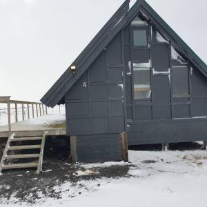 una casa negra con una rampa en la nieve en Árheimar 4 cosy holiday home, en Arabaer