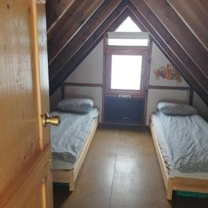 a attic room with two beds and a window at Árheimar 4 cosy holiday home in Arabaer