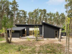 a black house in the woods with trees at Holiday Home Simona - 800m from the sea in Bornholm in Vester Sømarken