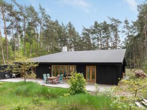 a black house in the woods with a deck at Holiday Home Simona - 800m from the sea in Bornholm in Vester Sømarken