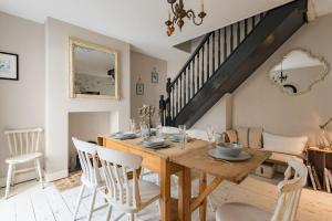 a dining room with a wooden table and white chairs at The House in Deal in Deal