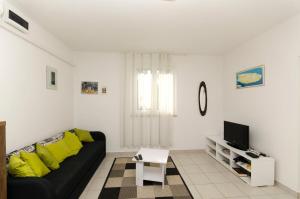 a living room with a black couch and a tv at House Bojan in Supetar